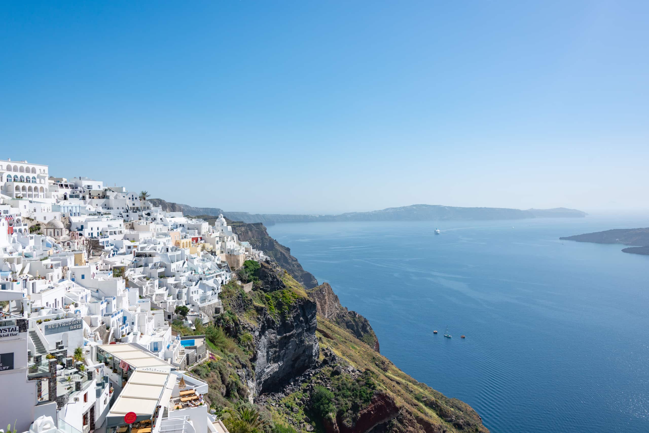 Aerial sweep of white houses above a tranquil turquoise sea