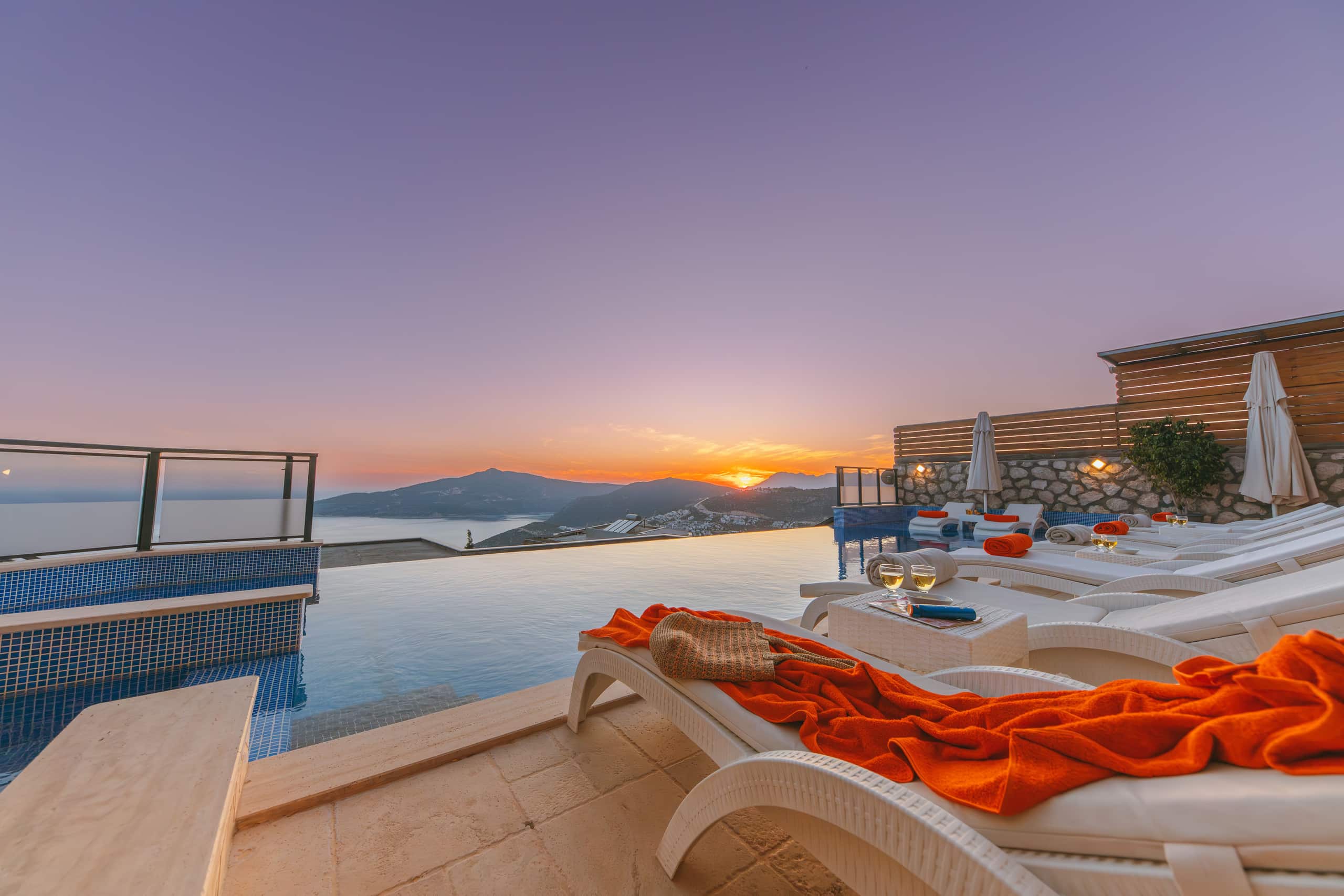 Sunbeds along the pool edge as the sky turns rose at dusk