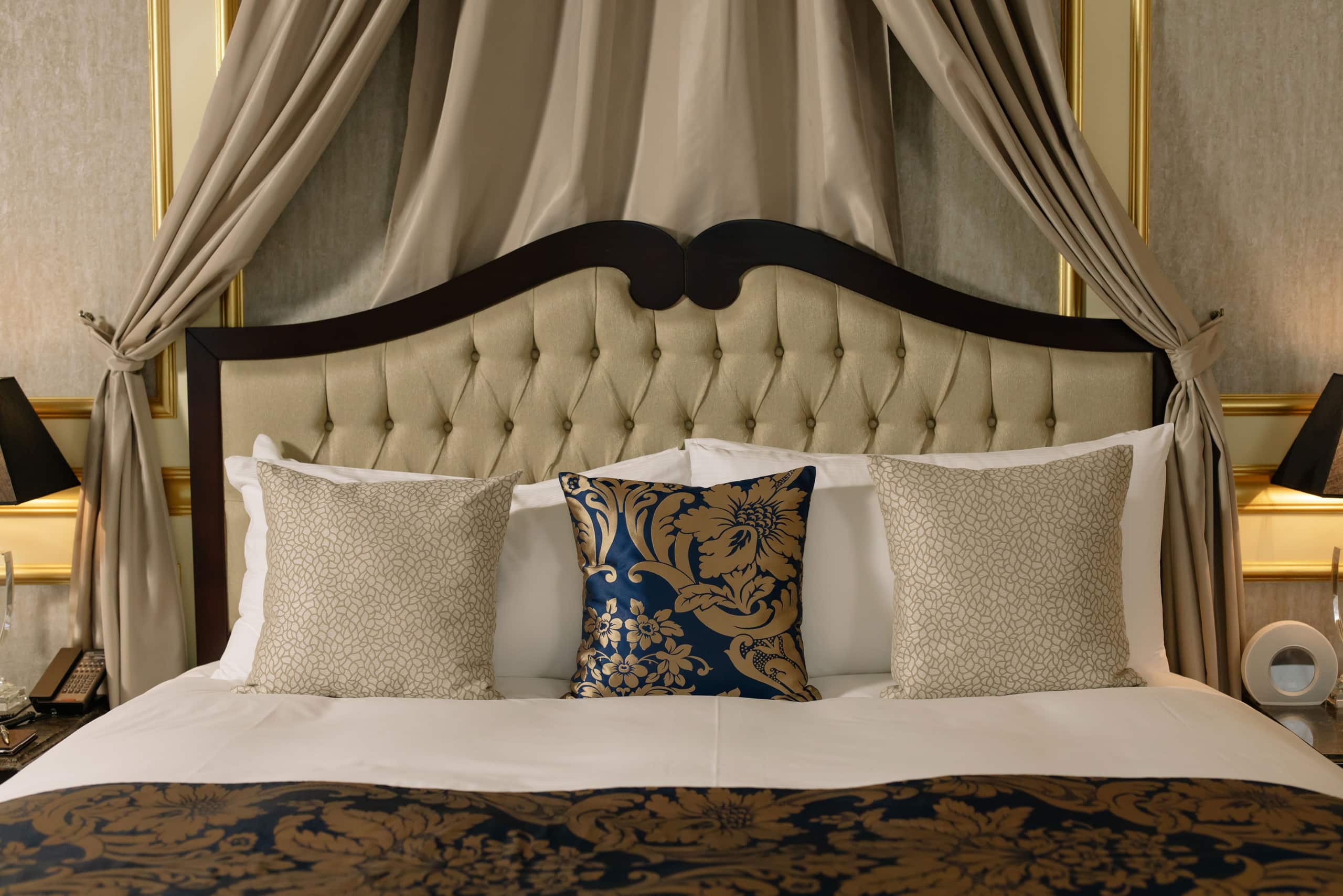Restored suite with carved wooden bed and luxurious curtains
