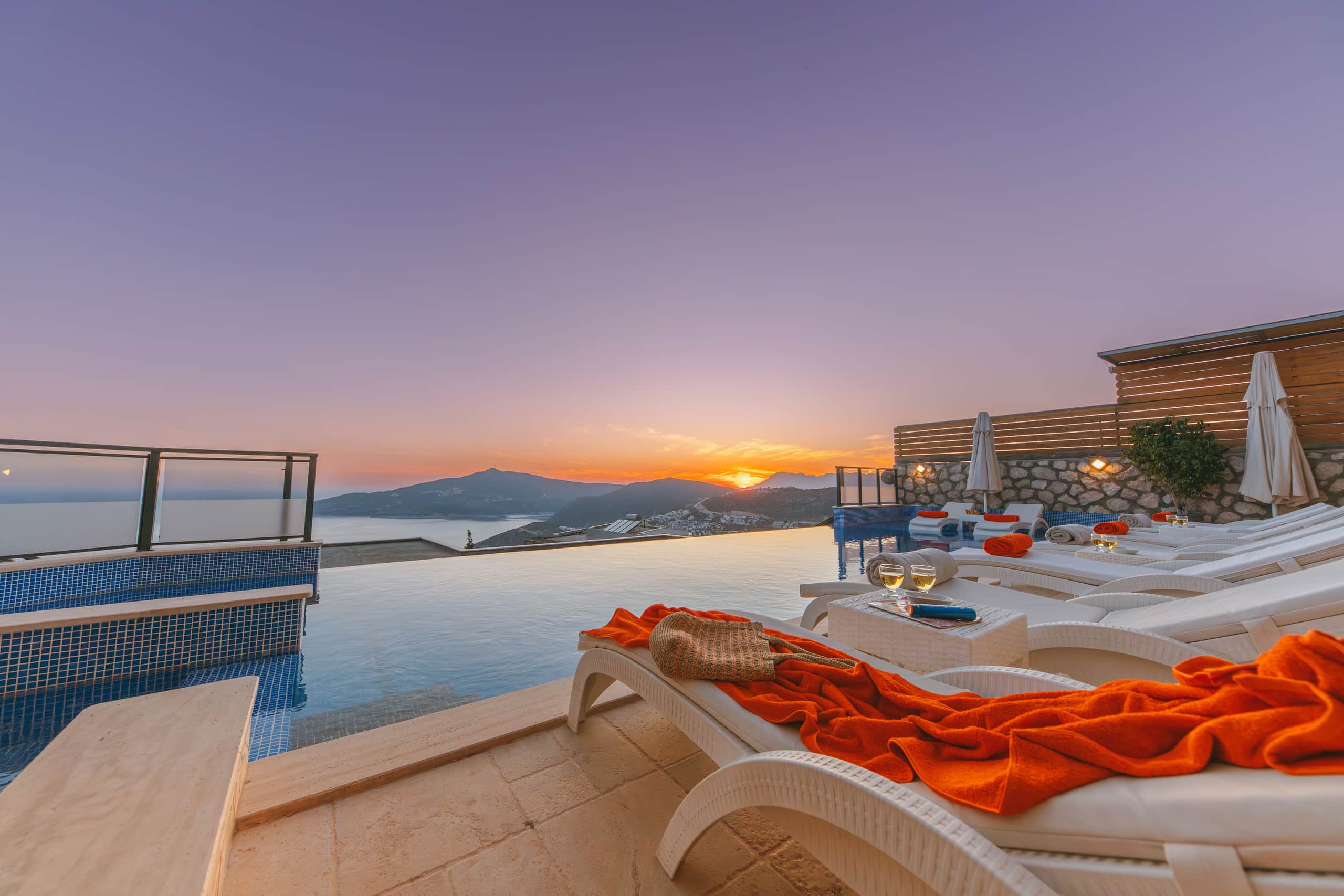 Sunbeds along the pool edge as the sky turns rose at dusk