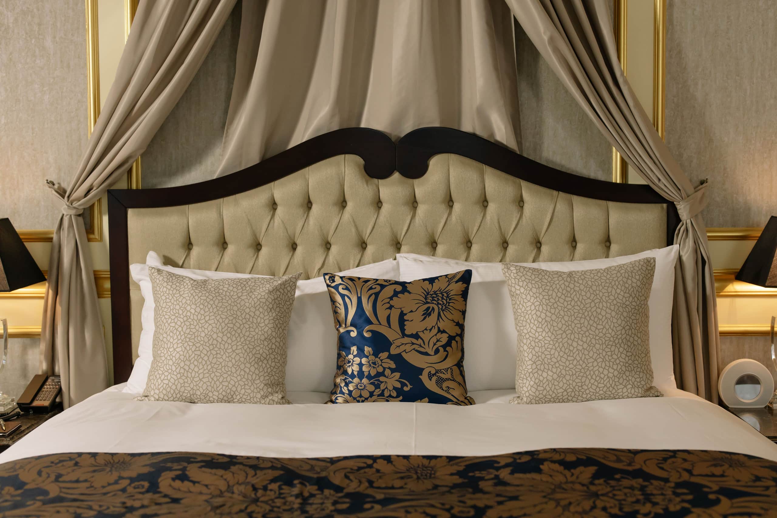 Restored suite with carved wooden bed and luxurious curtains